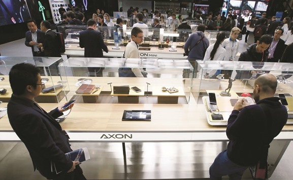 People look at ZTE Axon mobile phones during the Mobile World Congress in Barcelona, Spain. The restrictions to be set by the US Commerce Department will make it difficult for ZTE Corp to acquire US products.
