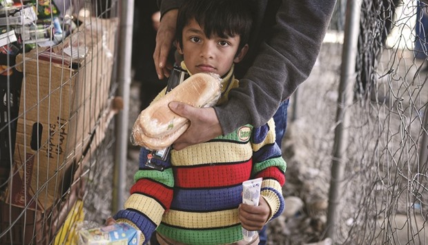 A boy with his father receive food yesterday in the makeshift camp at the Greek-Macedonian border near the village of Idomeni.