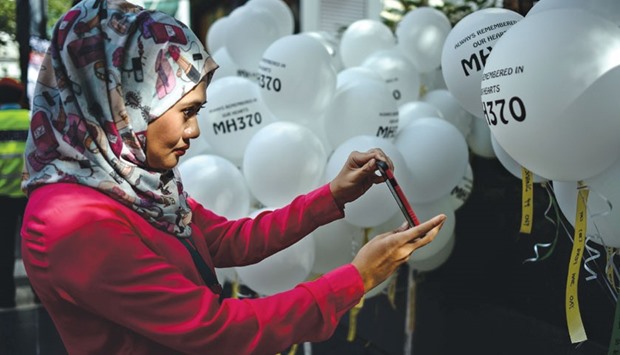 A woman takes pictures of balloons with names of the missing Malaysia Airlines ill-fated flight MH370 during a memorial event in Kuala Lumpur yesterday.