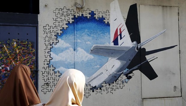 Women look at a mural of MH370 two years after it disappeared, in Kuala Lumpur on Monday.