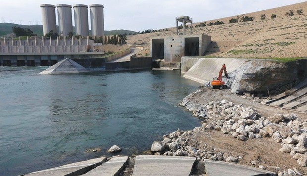 An employee operates an excavator at the Mosul Dam.