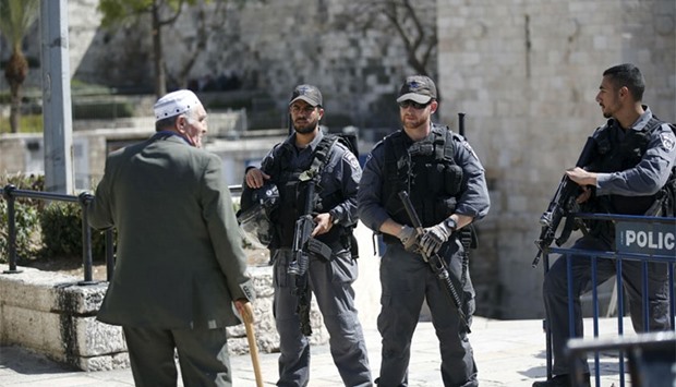 A Palestinian man looks at Israeli policemen as they guard near the scene where Israeli police spokesperson said a Palestinian woman tried to stab Israeli border policemen in Jerusalem's Old City. Reuters