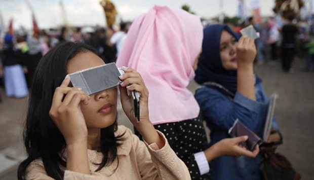 People test filters for watching a solar eclipse near the Ampera Bridge on the Musi River a day before thousands of people are expected to gather to witness the event in Palembang.