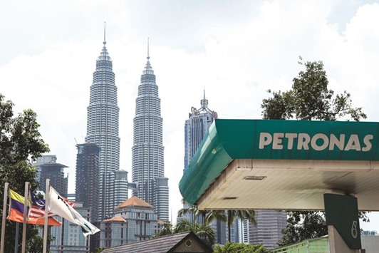 A Petronas gas station stands in front of the Petronas Twin Towers in Kuala Lumpur. Petronas last month posted its third loss in five quarters, announced plans to cut 1,000 jobs and said it may need to raise funds and tap cash reserves to cover capital expenditure and dividends.