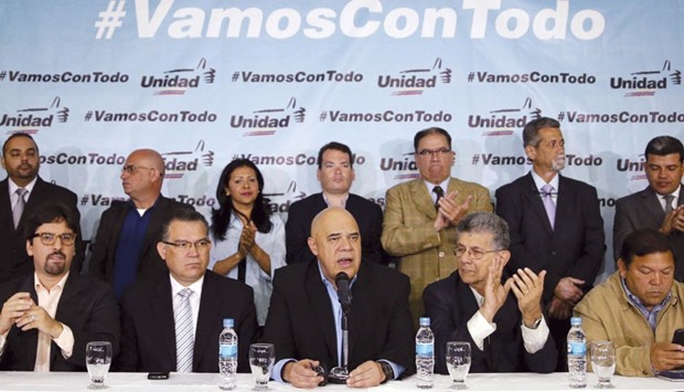 Jesus Torrealba (centre), secretary of Venezuelau2019s coalition of opposition parties (MUD), talks to the media next to his fellow politicians during a news conference in Caracas. The message on the backdrop reads: u201cWith the people and the constitution, we are going with everythingu201d.