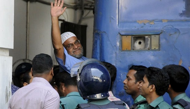 Bangladeshi Jamaat-e-Islami party leader, Mir Quasem Ali waving his hand as he enters a van at the International Crimes Tribunal court in Dhaka on November 2, 2014.