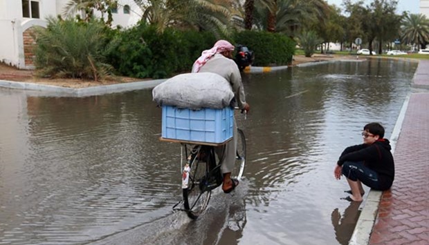 A man rides a bicycle in a flooded street following a heavy rain storm in Abu Dhabi.  
