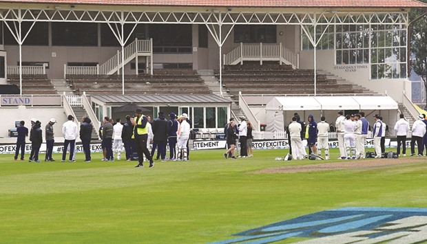 South Africa and New Zealand players and officials stand in the middle of the field after fire alarm in the main grandstand during the first Test in Dunedin yesterday. (AFP)