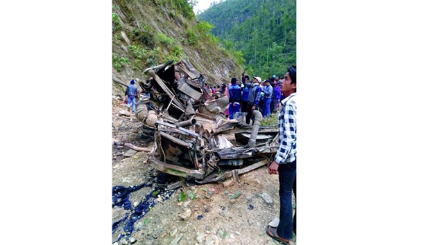 People gather along the wreckage of a bus after it veered off a hilly road in Jajarkot district of Nepal on Thursday.