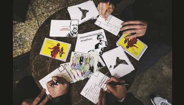 People write postcards to journalists in detention in Istanbul yesterday. Turkish journalists and opposition lawmakers protested yesterday in Istanbul against the detention of reporters, as a crackdown on the media has accelerated after the failed coup against Erdogan.