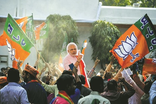 Supporters of Bhartiya Janata Party (BJP) hold a cutout of Prime Minister Narendra Modi as they celebrate elections results at the party headquarters in New Delhi yesterday.