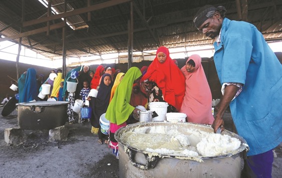 A volunteer serves internally displaced Somalis with cooked food from the United Nations World Food Programme (WFP) feeding programme at the Sorrdo camp in Mogadishuu2019s Hodan district.