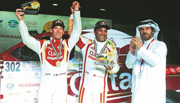 Winner Nasser al-Attiyah (C) and Mathieu Baumel with the winneru2019s trophy given by Mohammed Ben Sulayem, president of the Automobile and Touring Club of the UAE.
