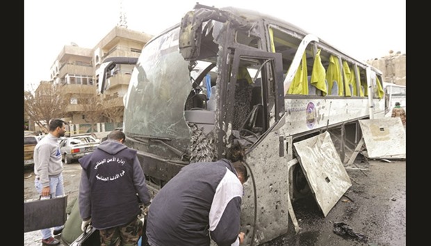 Syrian forensics examine a damaged bus at the scene of a bombing following twin attacks targeting pilgrims in Damascusu2019 Old City yesterday.