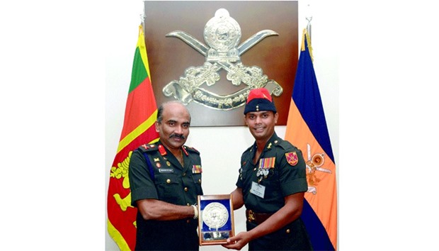 Lieutenant General Crishanthe de Silva (L) poses as he hands over a memento to Sri Lankan national cricketer Sergeant Asela Gunaratne.