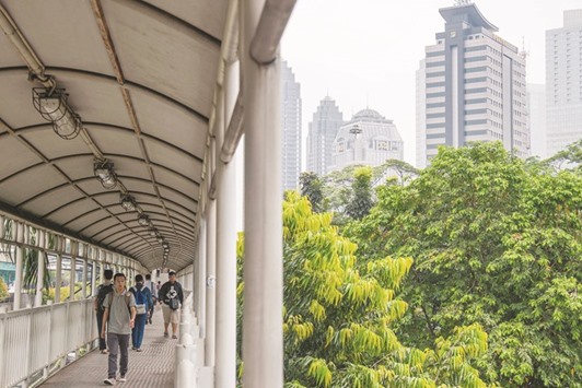 Commuters walk along a footbridge as commercial buildings stand in Jakarta. As one of Asiau2019s fastest-growing economies and the most populous Muslim nation in the world, Indonesia is billing itself as a natural home for Middle Eastern investment at a time when the US is turning inward.