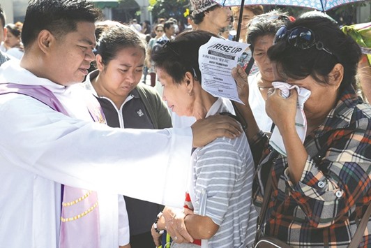 A priest blesses one of the relatives of victims of extra-judicial killings in President Rodrigo Duterteu2019s drug war during a gathering on the grounds of a church in Manila.