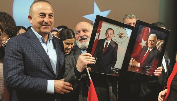 Turkish Foreign Minister Cavusoglu with a supporter holding portraits of Turkish President Erdogan and Prime Minister Yildirim at the end of a political rally on Turkeyu2019s upcoming referendum, in Metz, France.