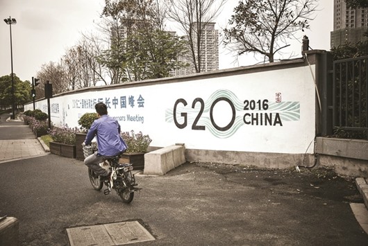 A man rides a scooter past signage for the Group of 20 summit in Hangzhou, China, on September 5, 2016. A document prepared by the EU ministers sets out the position of all European delegations for this yearu2019s G20 summit in Baden Baden in Germany on March 17-18.