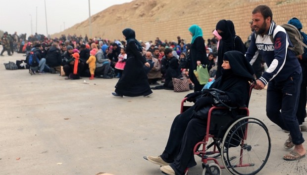 Displaced Iraqi people who have fled their homes because of the clashes, wait to be taken to safe pl