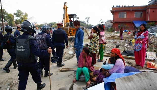 Nepalese homeless people watch police after a makeshift camp for people displaced by the 2015 earthquake was demolished by the authorities in Kathmandu on Tuesday.
