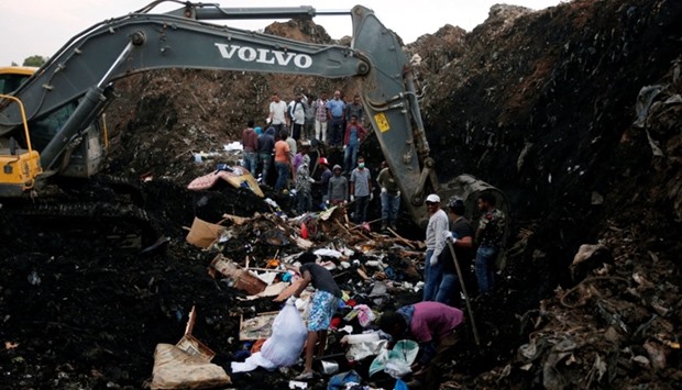 Rescue workers watch as excavators dig into a pile of garbage in search of missing people following a landslide when a mound of trash collapsed on an informal settlement at the Koshe garbage dump in Ethiopia's capital