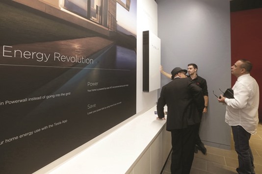 A Tesla representative (centre) demonstrates the Tesla Powerwall battery storage device to potential customers at its store in Sydney. Australian tech entrepreneur Elon Musk promised to install and get working a Tesla battery storage system to prevent blackouts in South Australia.