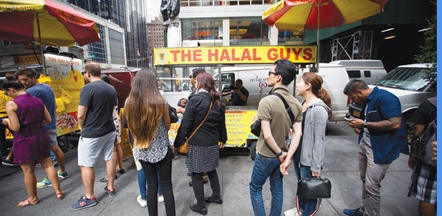 Customers stand in line at The Halal Guysu2019 food cart on West 53rd Street and 6th Avenue in New York (file). Halal Guys, which started as a street cart serving meat dishes in New York City, has proved so popular that the company plans 300 sit-down restaurants across the US in the next several years. Islamic finance in general is increasingly making inroads into the US in a variety of forms, but widely out of the radar of the broader public.