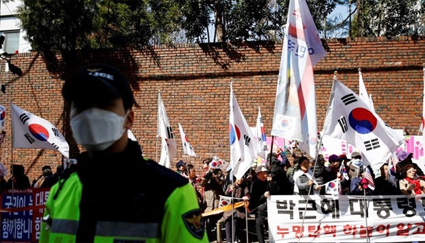 A police officer stands guard in front of supporters of Park Geun-hye