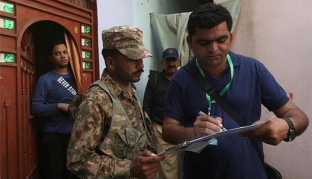 A census enumerator, along with a Pakistan Army soldier, notes details outside a house during Pakistanu2019s 6th population census in Karachi on Wednesday.