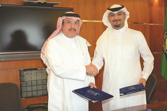 Al-Ageel and Janahi shaking hands after signing the partnership contract.
