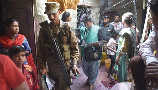 An official from the Pakistan Bureau of Statistics (C) is flanked by an army soldier as they left after collecting information from residents during a census in a narrow street in Karachi yesterday.