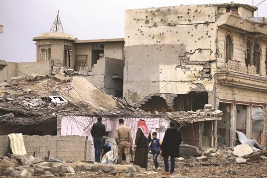 An Iraqi family inspect their home which was destroyed by clashes during a battle between Iraqi forces and Islamic State militants, in the city of Mosul.