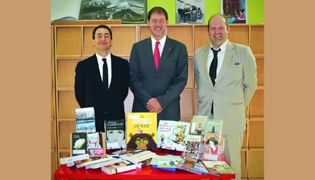 French ambassador Eric Chevallier (left) receiving the books from Canadian ambassador Adrian Norfolk (centre) as another official looks on.