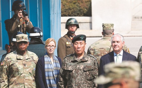 US Secretary of State Rex Tillerson (right) stands with military commanders as two North Korean soldiers (top) look at the border village of Panmunjom, which has separated the two Koreas since the Korean War.