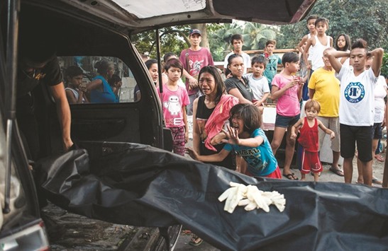 File photo shows Analyn Roxas (centre), 26, mourning with her sister as coroners take away her partner, Valien Mendoza, a suspected drug dealer, who was gunned down by unidentified assailants in Manila.