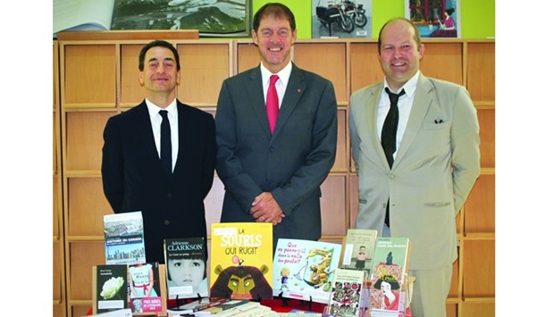 French Ambassador Eric Chevallier (left) receiving the books from Canadian Ambassador Adrian Norfolk (centre) as another official looks on.