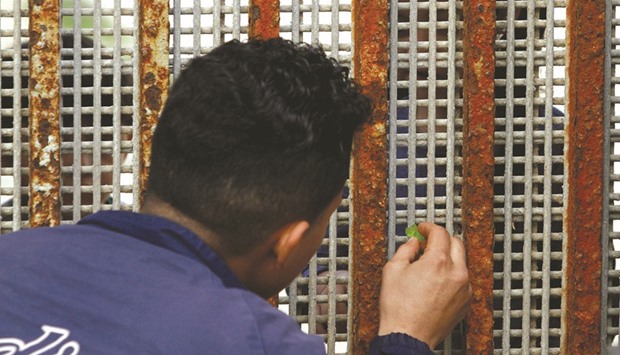 A man deported from the US seven months ago receives candy from his nephew across a fence separating Mexico and the United States as photographed from Tijuana, Mexico.