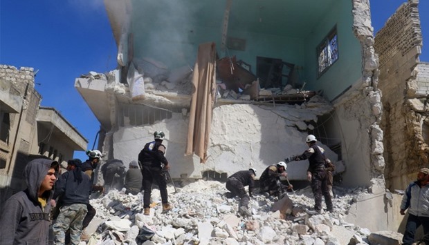 People and civil defence personnel remove rubble  after clashes in Idlib city
