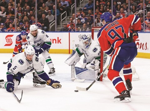 Vancouver Canucksu2019 Richard Bachman (centre) and Luca Sbisa (left) try to stop Edmonton Oilersu2019 Connor McDavid from scoring during the NHL game in Edmonton, Alberta. (USA TODAY Sports)