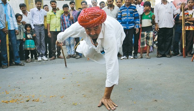 A man performs a stunt with a bamboo stick as part of Holi celebrations locally known as u201cGareu201d festival outside a temple in Ahmedabad yesterday.