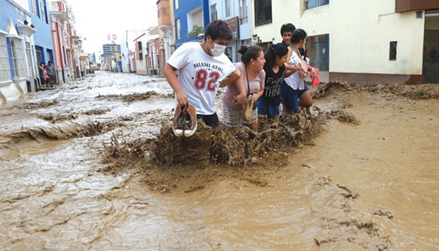 Local residents wade through the water as a flash flood hits the city of Trujillo, 570kms north of Lima, bringing mud and debris.