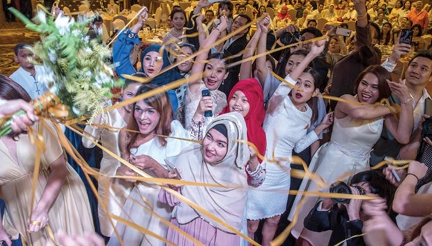 Family and friends of a newlywed couple pull on ribbons attached to a flower bouquet during the coupleu2019s wedding reception at the Al Meroz hotel in Bangkok.