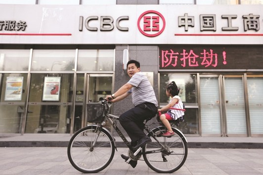 A man and his daughter ride a bicycle past a branch of the Industrial and Commercial Bank of China in Beijing. Chinese lenders in 2016 likely posted their lowest interest margins since the global financial crisis, due to higher costs and fewer lucrative lending options, with the going set to get tougher as the key gauge of profitability stays under pressure.