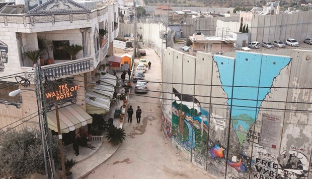 A general view shows the Walled-Off Hotel (left), Banksyu2019s newly-opened hotel, standing next to the controversial separation wall, in the occupied West Bank town of Bethlehem yesterday.