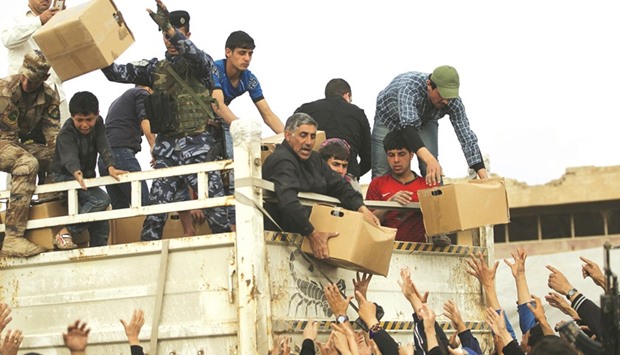 Displaced Iraqis from Mosul receive aid parcels as they arrive at the Hamam al-Alil camp yesterday. Right: Displaced Iraqis from Mosul at the Hamam al-Alil camp yesterday, during the government forces ongoing offensive to retake the western parts of the city from Islamic State (IS) group fighters.