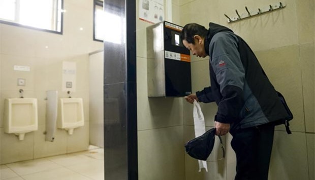 A man uses an automatic toilet paper dispenser that uses facial recognition technology at a public toilet at the Temple of Heaven in Beijing on Tuesday.