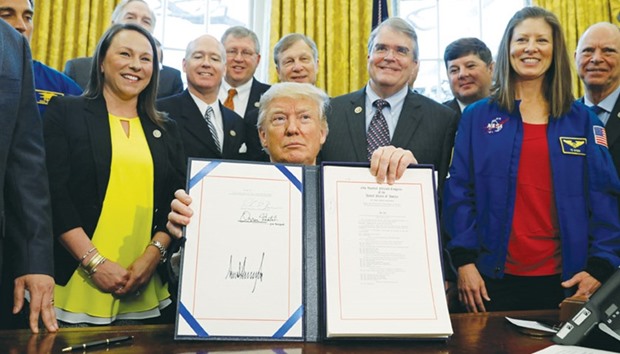 President Donald Trump holds up S442, the Nasa transition authorisation act, after signing it in the Oval Office of the White House in Washington.