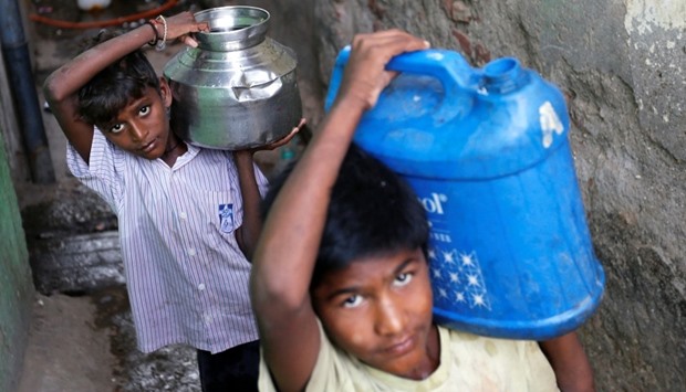 Boys carry containers filled with water from a communal tap