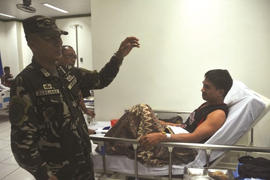 A Philippine military officer visits a soldier, wounded after a clash with the Abu Sayyaf group.